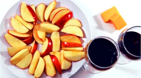 apples on white plate with cheese and wine