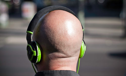 back view of bald guy with green headphones