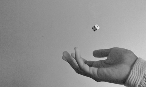 hand tossing 1 die in the air black and white